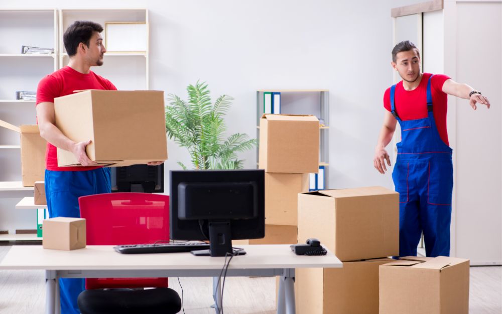 Professioneller Umzug eines Büros mit Umzugshelfern, die Schreibtische und Computer transportieren